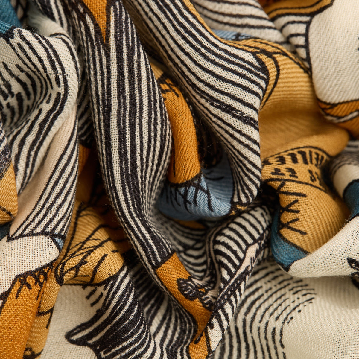 A woman stands facing forward, wearing a grey long-sleeve coat and skirt, black shoes, and the INOUI EDITIONS Stack of Books Wool Scarf in navy, a colorful, hand-printed accessory from INOUI, made in India, on a white background.