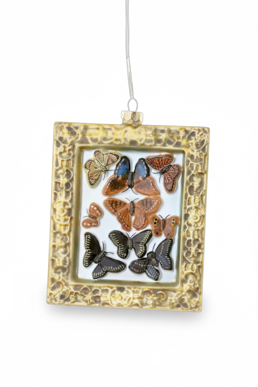 A VICTORIAN BUTTERFLY ORNAMENT featuring a collection of butterfly illustrations inside an ornate gold rectangular hanging frame.