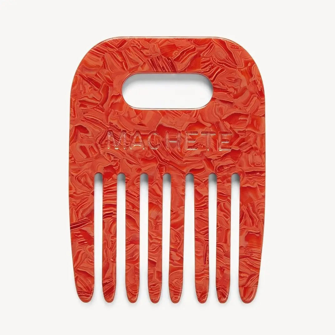 The MACHETE - NO. 4 COMB IN POPPY is a red marbled wide-tooth comb crafted from Italian acetate, featuring a rectangular handle cutout and "MACHETE" embossed on the front. Ideal for curly hair and shown against a plain, light background.