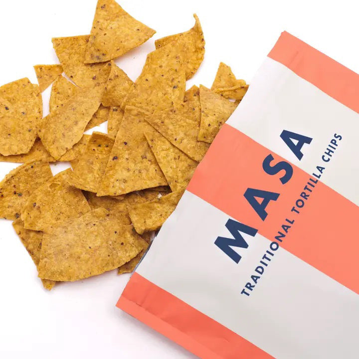 A bag of ANCIENT CRUNCH - TRADITIONAL TORTILLA CHIPS by ANCIENT CRUNCH with red and white stripes stands upright, labeled &quot;Original&quot; and &quot;No Seed Oils,&quot; highlighting its seed oil-free recipe with crunchy chips scattered in front.