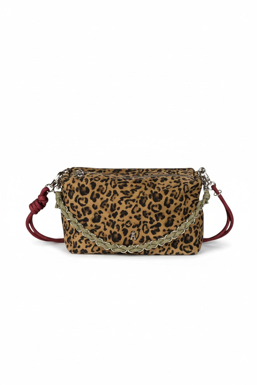The CRAIE STUDIO - MINI HALO LEO SEPIA BAG by CRAIE STUDIO is a striking leopard-print suede leather handbag, showcasing a silver chain and vivid red leather shoulder strap, beautifully presented against a white background.