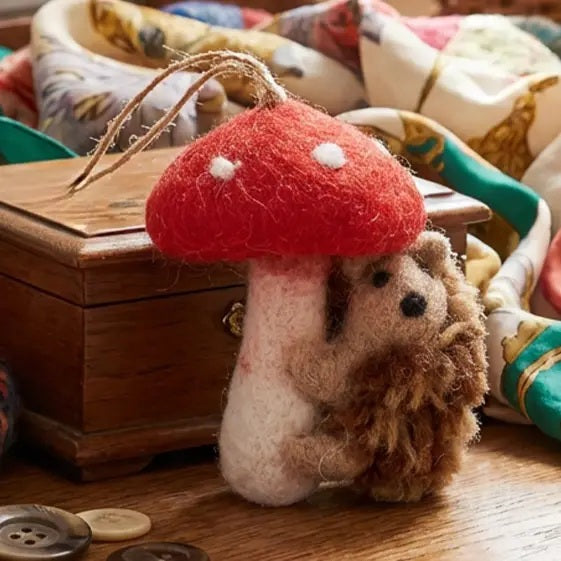 Handmade wool TOADSTOOL HEDGEHOD ORNAMENT featuring a hedgehog hugging a needle felted toadstool with a hanging loop.