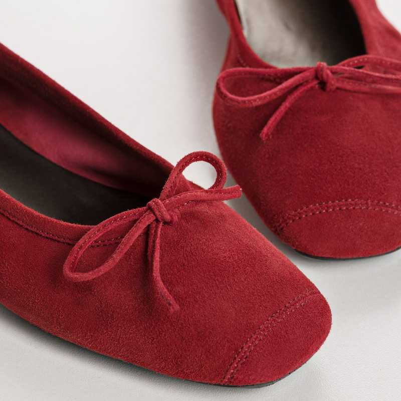 A person wearing blue jeans and REQINS - HARMONY Suede Ballerina Flats in cerise stands on a light-colored floor.