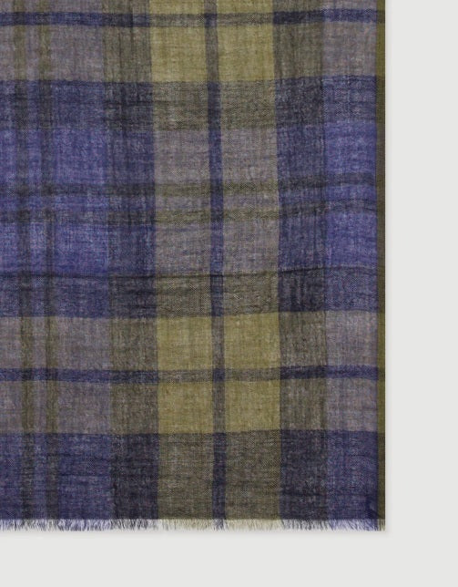 A young person with short dark hair wears a navy sweater and the HARTFORD Tartan Wool Scarf in Navy, Indigo, and Olive from HARTFORD, tied loosely around their neck, looking directly at the camera against a plain light background.