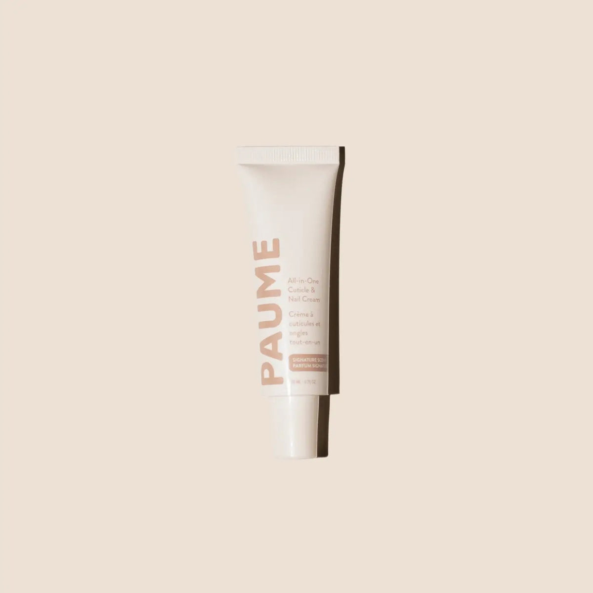 A tube of PAUME - ALL IN ONE CUTICLE AND NAIL CREAM by PAUME, infused with plant-based keratin, stands upright against a light beige background, showcasing minimal modern packaging in soft pink and white.