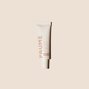 A tube of PAUME - ALL IN ONE CUTICLE AND NAIL CREAM by PAUME, infused with plant-based keratin, stands upright against a light beige background, showcasing minimal modern packaging in soft pink and white.