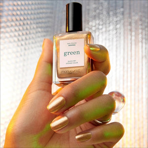A bottle of MANUCURIST INC GREEN™ Nail Polish in Shimmer, a vegan and cruelty-free gold shade featuring “Quick Dry Intense Color” and topped with a black cap.