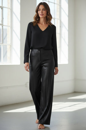 The MANHATTAN PANT by MOMONI is a pair of high-waisted, straight leg pants crafted from black faux leather, featuring a button and zip closure and displayed against a plain white background.