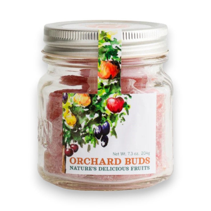 A glass jar labeled &quot;BUTTERFIELDS - ORCHARD BUDS,&quot; branded as BUTTERFIELDS with the tagline &quot;Nature&#39;s Delicious Fruits,” containing pink candies. The jar has a metal lid and a colorful label featuring illustrations of fruit-bearing branches with apples, plums, and peaches.