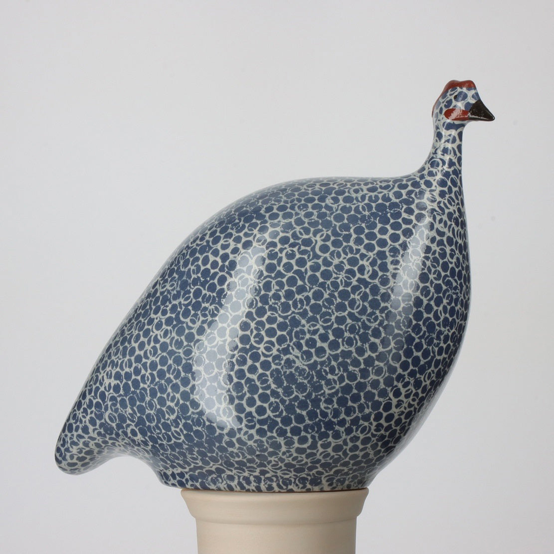 The LES CERAMIQUES DE LUSSAN ceramic guinea features an electric blue body with white spots and a red accent on its head, showcasing elegant French craftsmanship.