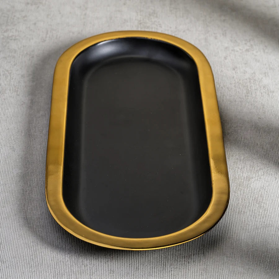 The ZODAX OVAL TRAY - BLACK WITH GOLD BORDER is a modern serving tray with a matte black oval base and a bold gold rim, shown elegantly on a white background.