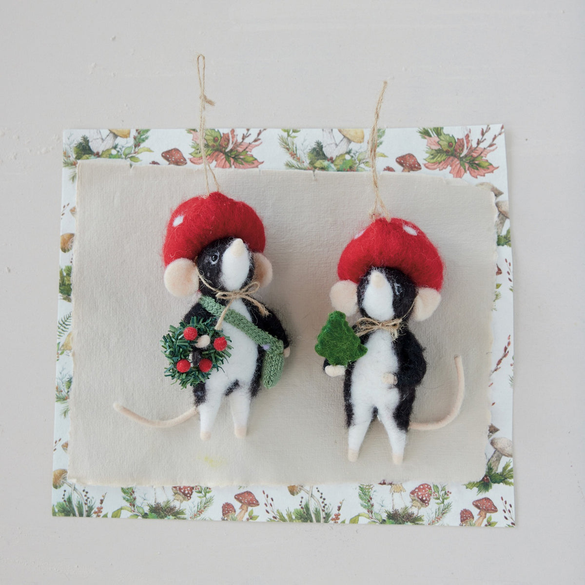 Two WOOL FELT MOLE IN MUSHROOM HAT ORNAMENTs shaped like mice; one holds a green sprig and the other a small wreath.