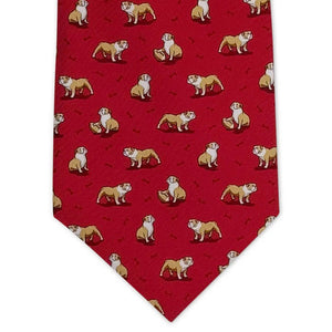 The BIRD DOG BAY - Bulldog Bonanza Silk Tie in Red features a repeating pattern of tan and white bulldogs with black bones on printed silk. The tie is displayed rolled, pointed end forward.
