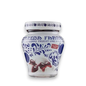 A white and blue ceramic jar featuring intricate floral and geometric patterns, labeled "FABBRI - AMARENA CHERRIES IN SYRUP" in blue text under the brand name "GOURMET FOOD SOLUTIONS." The jar contains Italian tart cherries in syrup, promising a delightful sour taste and displaying a red "Gluten Free" label. The jar is photographed against a light gray background.