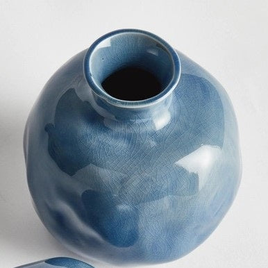 Two round, glossy blue ceramic NAPA HOME AND GARDEN - BLUE NARINE BUD VASES (Large) with narrow openings and crackle glaze patterns, positioned closely together on a plain white background.