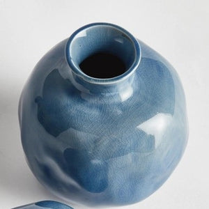 Two round, glossy blue ceramic NAPA HOME AND GARDEN - BLUE NARINE BUD VASES (Large) with narrow openings and crackle glaze patterns, positioned closely together on a plain white background.