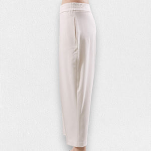 The MEIMEIJ - PONTE PULL ON TROUSER, a pair of beige, high-waisted, straight-leg pull-on trousers from MEIMEIJ, is displayed against a light textured background. These pants feature an elastic waistband, side pockets, and a simple, minimalist design.