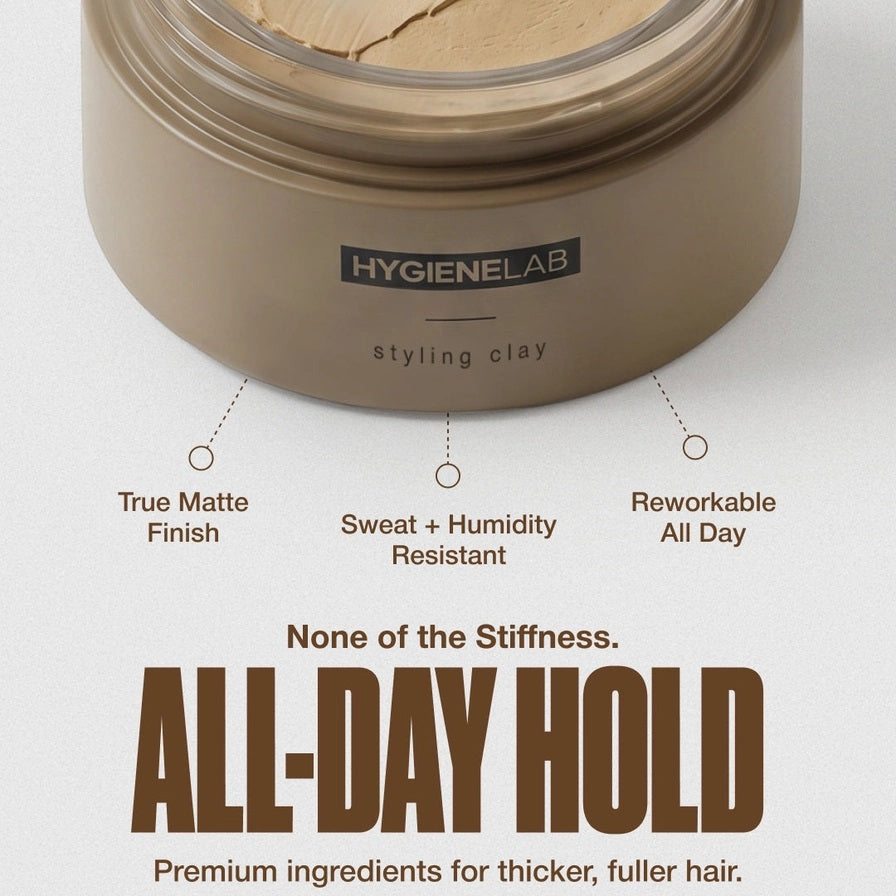 An open, round container of HYGIENELAB - STYLING CLAY displays the smooth, light gray clay inside with a swirled surface. This styling clay from HYGIENELAB provides a medium-strong hold and a natural matte finish.