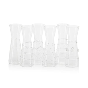Six ZALLI SINGLE SERVE GLASS CARAFES by ZODAX, each featuring a unique etched design, are arranged on a reflective silver tray with a blurred green background.