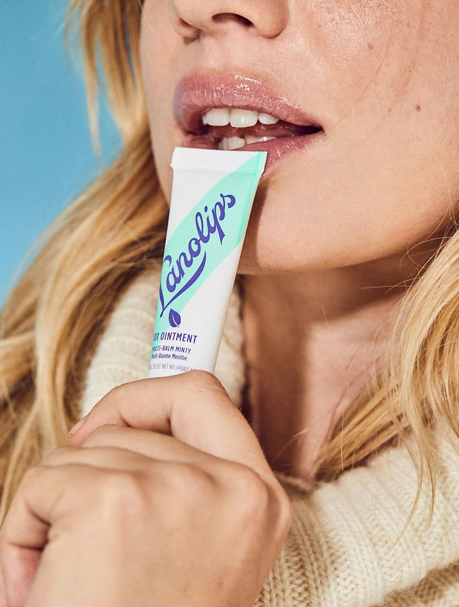A white and teal tube of LANOLIPS 101 OINTMENT MULTI-BALM MINTY, featuring bold blue text and a sleek slanted design on the front—this natural lip balm from LANOLIPS is enriched with lanolin ointment to soothe and moisturize dry, chapped lips.