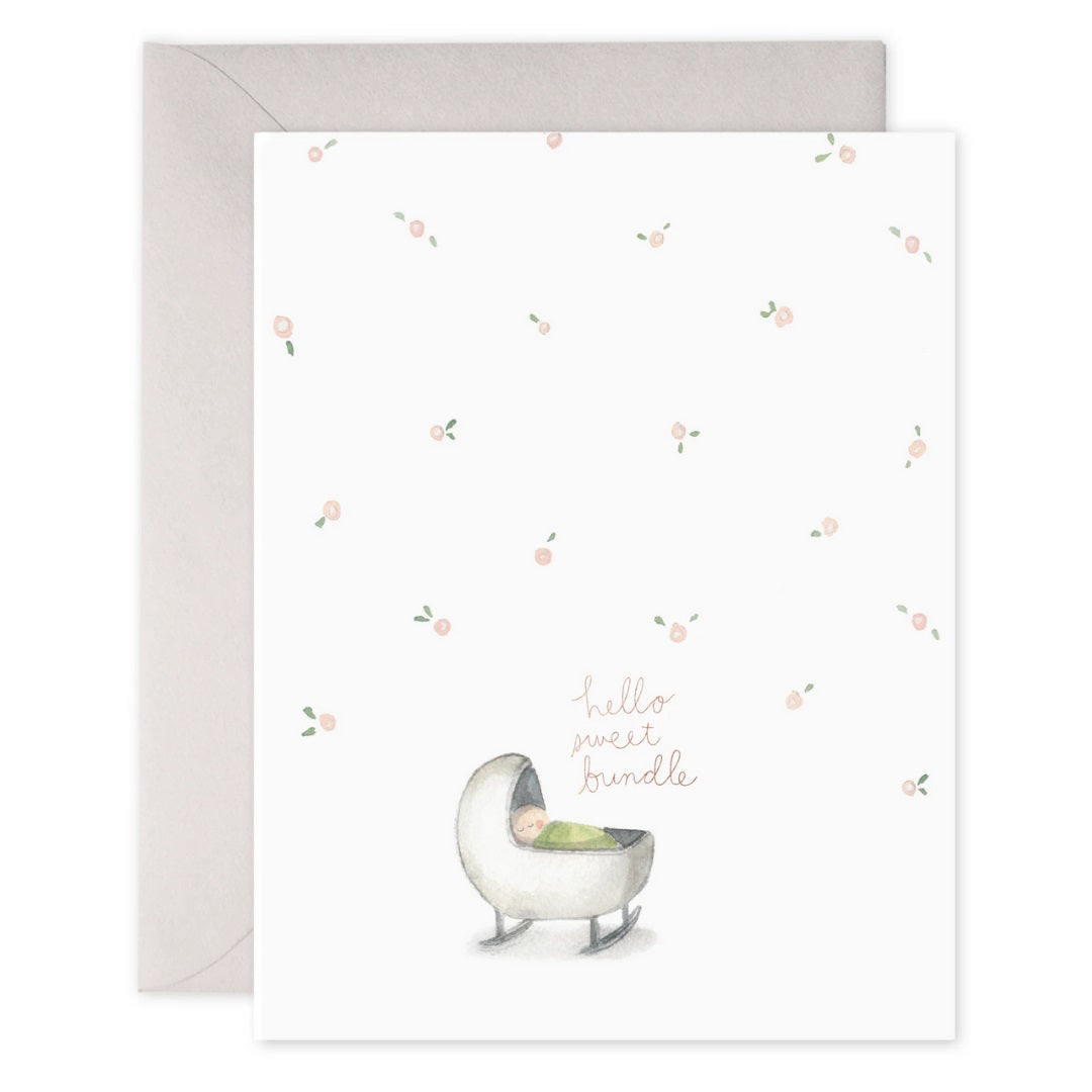 E. FRANCES PAPER - HELLO SWEET BUNDLE greeting card features a baby in a cradle with scattered pink flowers on a white background. The text "hello sweet bundle" is printed on heavyweight paper with gold foil accents, and the edge of the card is visible.