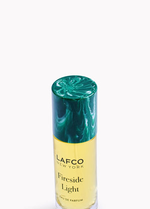 A yellow bottle of LAFCO - FINE FRAGRANCE, FIRESIDE LIGHT 10ML stands upright on a white background, featuring a marble-patterned green cap and reflecting the ambered vanilla notes of this vegan perfume.
