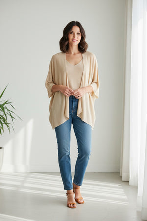 The MOMONI - DIVINA KNIT CARDIGAN is a chic brown, open-front piece with a draped, asymmetrical hemline. Crafted in Italy with wide sleeves, it's perfect as evening wear against a plain white backdrop.