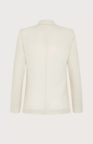 The SEVENTY VENEZIA single-breasted blazer from SEVENTY features a cream-colored fitted design with a notched lapel collar, two beige buttons at the front, and two front pockets. Made in Italy from textured lurex pique fabric, it includes a label inside the collar reading "Seventy.