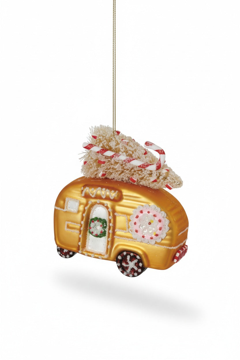A hand-painted gold CAMPER GINGERBREAD COOKIE ORNAMENT decorated with a wreath, a snowflake, and a bottle brush tree on the roof with a candy cane.