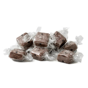 A clear bag of MOUTH PARTY - OMG BAG caramels, including sea salt caramel, is tied with a copper satin bow. The label says "Mouth Party Caramel OMG! NET WT. 6oz (170g)." Brand: MOUTH PARTY.