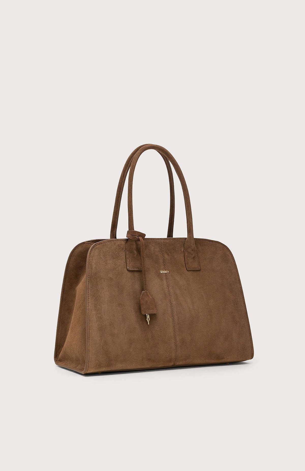 The SEVENTY VENEZIA suede leather bag in chocolate brown features two handles, a small padlock charm, and subtle gold branding on the front, displayed against a plain light background.