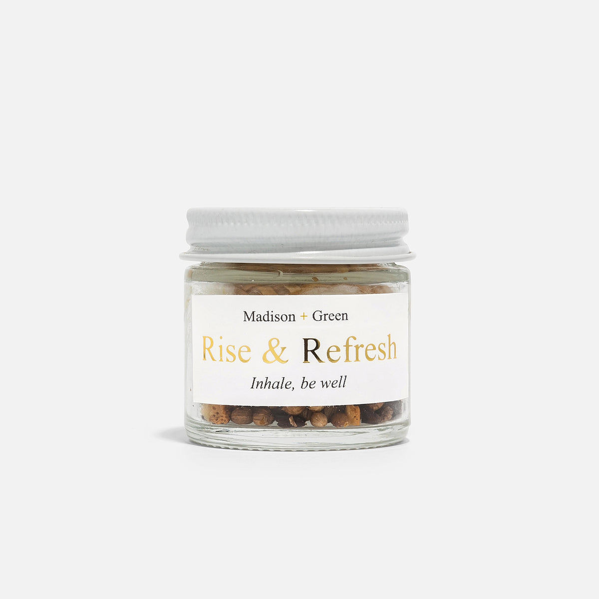 A small glass jar with a white screw-on lid labeled "MADISON GREEN - ROSE AND REFRESH MORNING AROMATHERAPY INHALER," containing mixed dried botanicals for natural stress relief, sits against a plain white background.