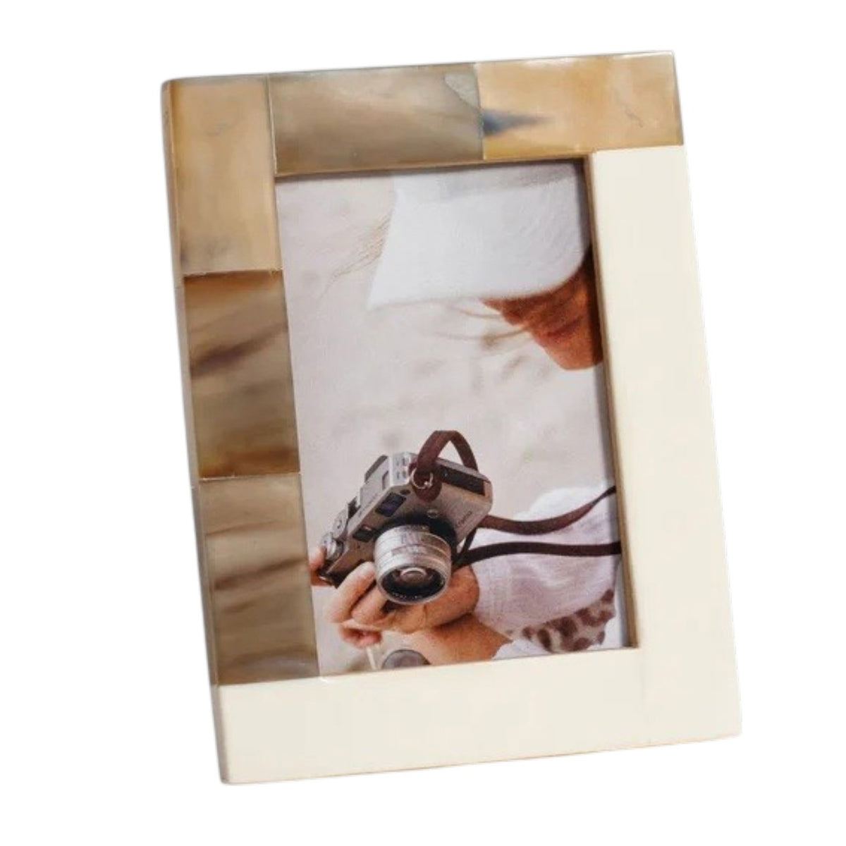 Close-up of the corner of the ZODAX WHITE HORN AND IVORY RESIN FRAME (4x6), elegantly crafted in soft beige tones. The frame displays a photo featuring hands holding a vintage camera, with the person's face partially out of view to emphasize the camera and hands.