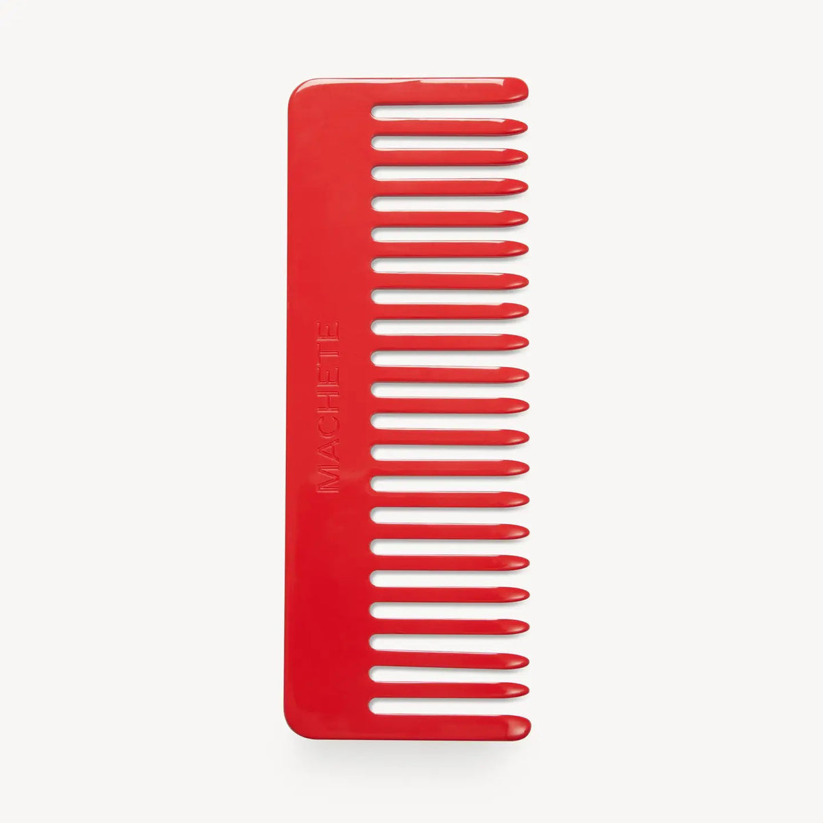 The MACHETE - NO. 2 COMB IN RUBY is a red, wide-tooth comb crafted from premium Italian acetate with rounded tips and flat edges. "MACHETE" is embossed on the handle, and it suits all hair types. Shown on a plain white background.