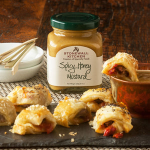 An 8 oz (227g) glass jar of STONEWALL KITCHEN - SPICY HONEY MUSTARD from Stonewall Kitchen, featuring a cream label with green and brown text and a black lid. This sweet and spicy mustard is gluten free, non-GMO, as indicated on the label.
