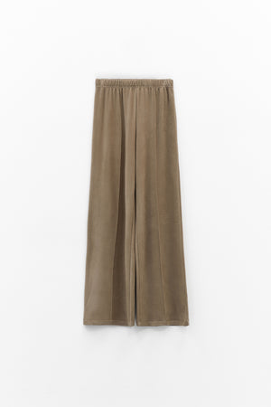 The ELEH - THE SCALA PULL ON SWEATPANT TROUSER by ELEH is a pair of loose-fitting, light brown, velvety pull-on trousers with an elastic waistband, shown against a plain white background.