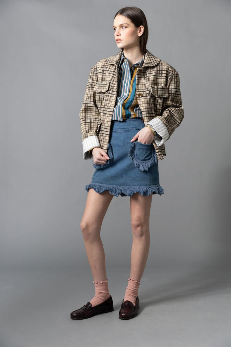 A woman stands sideways against a gray background, wearing the HOPE FOR FLOWERS - FOUR POCKET JACKET by HOPE FOR FLOWERS with a matching beige and brown plaid skirt, white socks, and dark brown heels. Her hair is pulled back as she looks slightly upward.