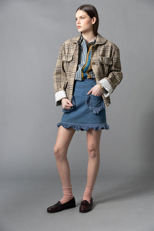 A woman stands sideways against a gray background, wearing the HOPE FOR FLOWERS - FOUR POCKET JACKET by HOPE FOR FLOWERS with a matching beige and brown plaid skirt, white socks, and dark brown heels. Her hair is pulled back as she looks slightly upward.