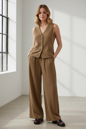 A person wearing ELEH CLASSIC WIDE LEG TROUSERS and a matching brown corduroy jacket, paired with brown shoes and large sunglasses, stands against a plain white background with hands in pockets.