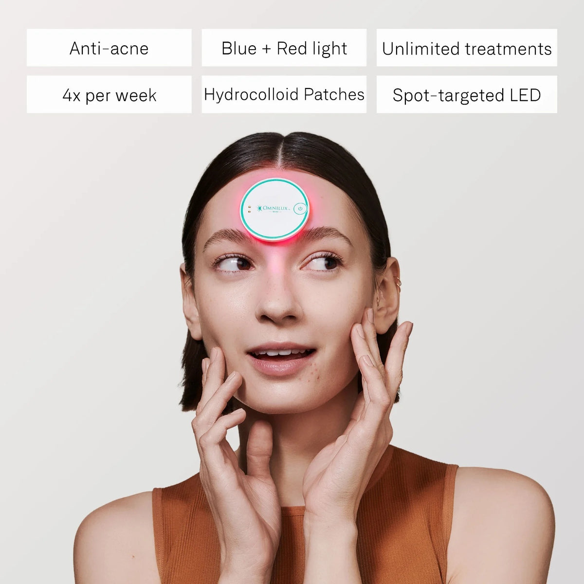 A round, white OMNILUX - BLEMISH ERASER KIT device from OMNILUX features a teal rim, power button, and logo; a soft pink light glows from underneath, showcasing its advanced blue and red light therapy technology.