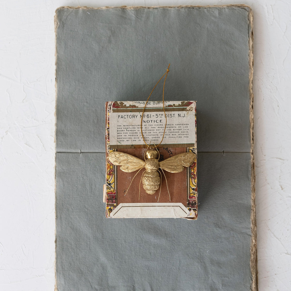 BEE ORNAMENT WITH WIRE LEGS by CREATIVE COOP, a gold resin bee hanging from a thin string with textured wings and thin wire legs in a polished gold finish.