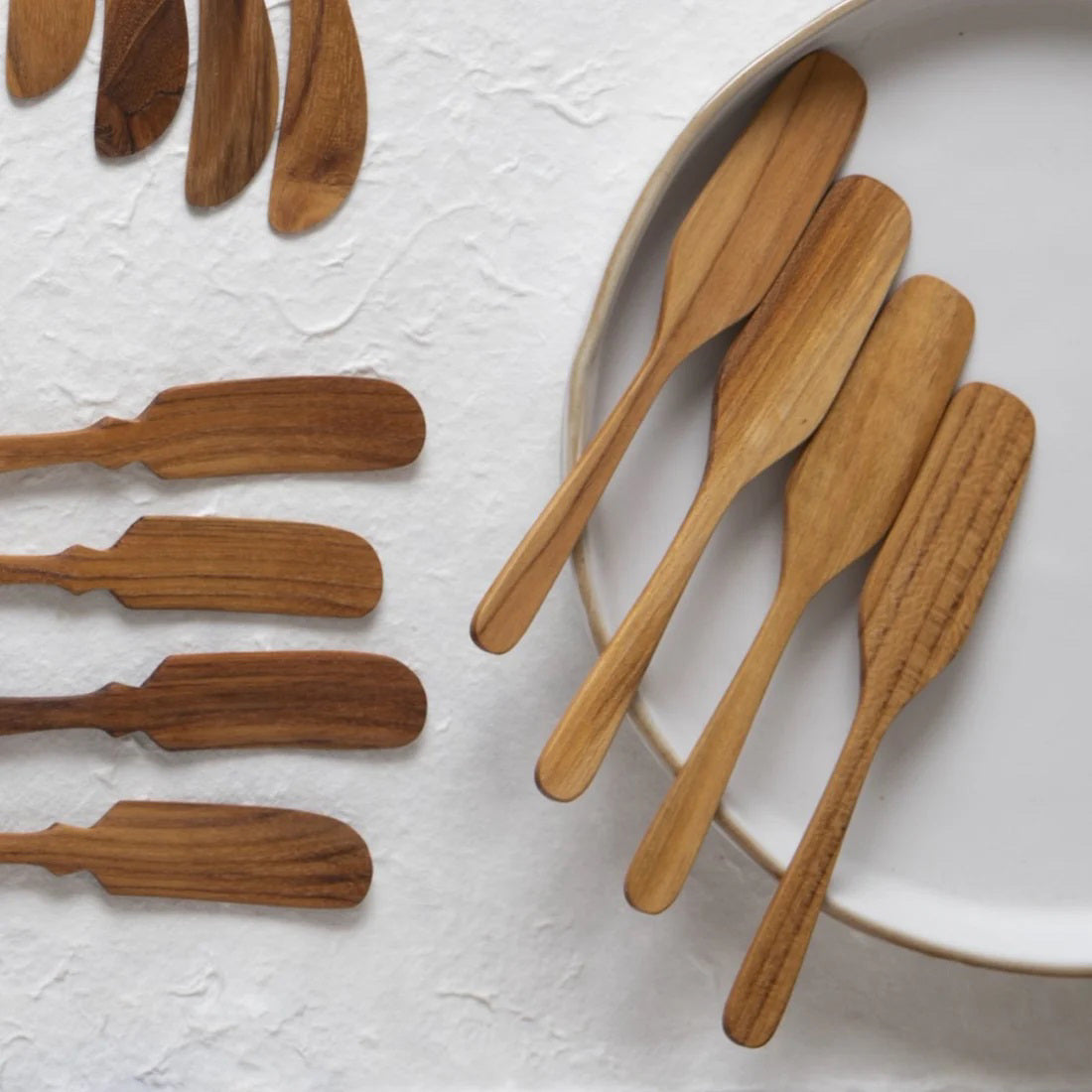 The BE HOME - TEAK OAR SPREADER set by BE HOME, INC includes four sustainably sourced teak wood spreaders with smooth, rounded handles and paddle-shaped blades, displayed side by side on a light gray background.