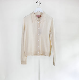 The ROSE & CROWN - CASHMERE CARDIGAN, a luxury long-sleeve button-up in custom-dyed magenta, hangs on a white hanger against a light gray background.