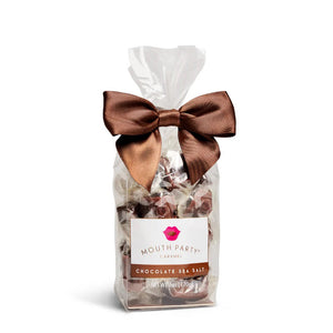 A clear bag of MOUTH PARTY - CHOCOLATE SEA SALT caramels from MOUTH PARTY, tied with a shiny brown ribbon. The label features a pink lips logo and product details.