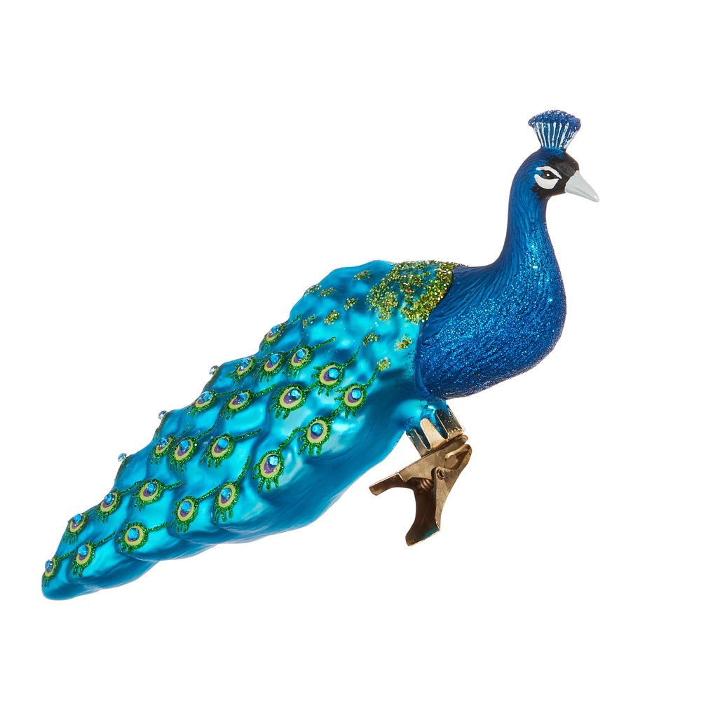 The RAZ IMPORTS PEACOCK ORNAMENT is a blue glass collectible featuring a long, glittery eye-patterned tail and a metal clip—perfect for adding unique decorative flair to your space.