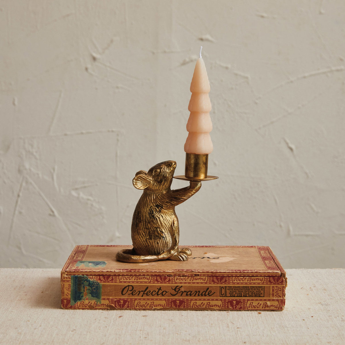 The CREATIVE COOP CAST ALUMINUM MOUSE TAPER HOLDER features a gold-colored mouse sitting upright and holding a candle cup on a plate with one paw.