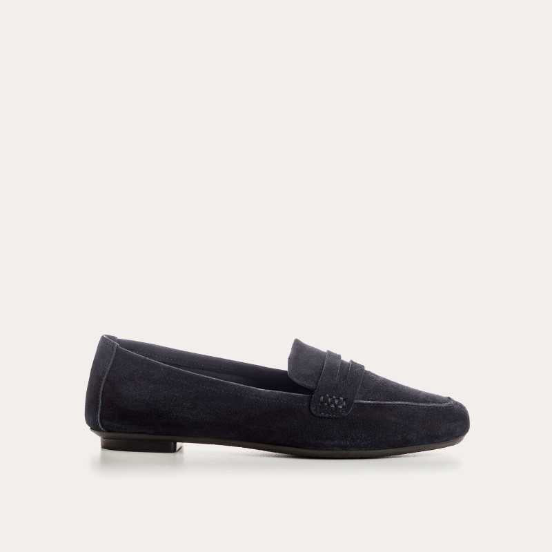 Six pairs of REQINS HEMA suede loafers in marine, featuring a classic penny loafer design and timeless silhouette, are displayed on a light tan surface in various blue and green shades.
