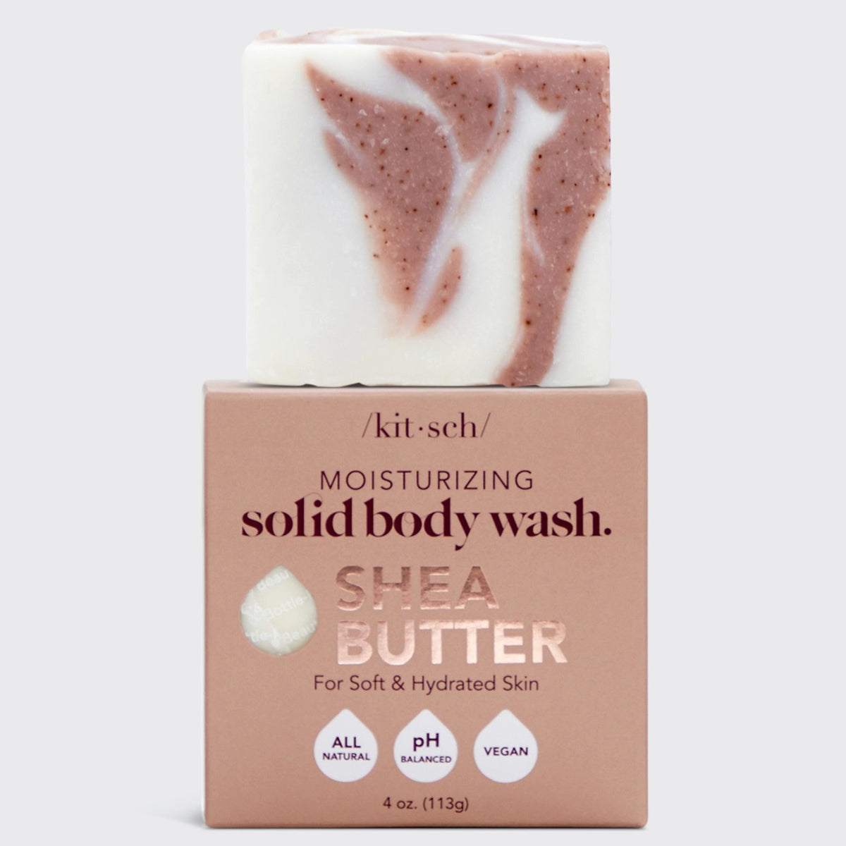 A bar of KITSCH - MOISTURIZING SHEA BUTTER BODY WASH with pink and white swirls rests on a pink box; this all-natural, pH balanced, vegan body wash leaves skin soft and hydrated.