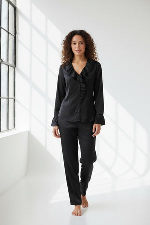 A woman with long dark hair wears the HINSON WU AMARA Long Sleeve Cotton Satin Shirt, featuring ruffled details on the collar and front, standing against a plain light background.