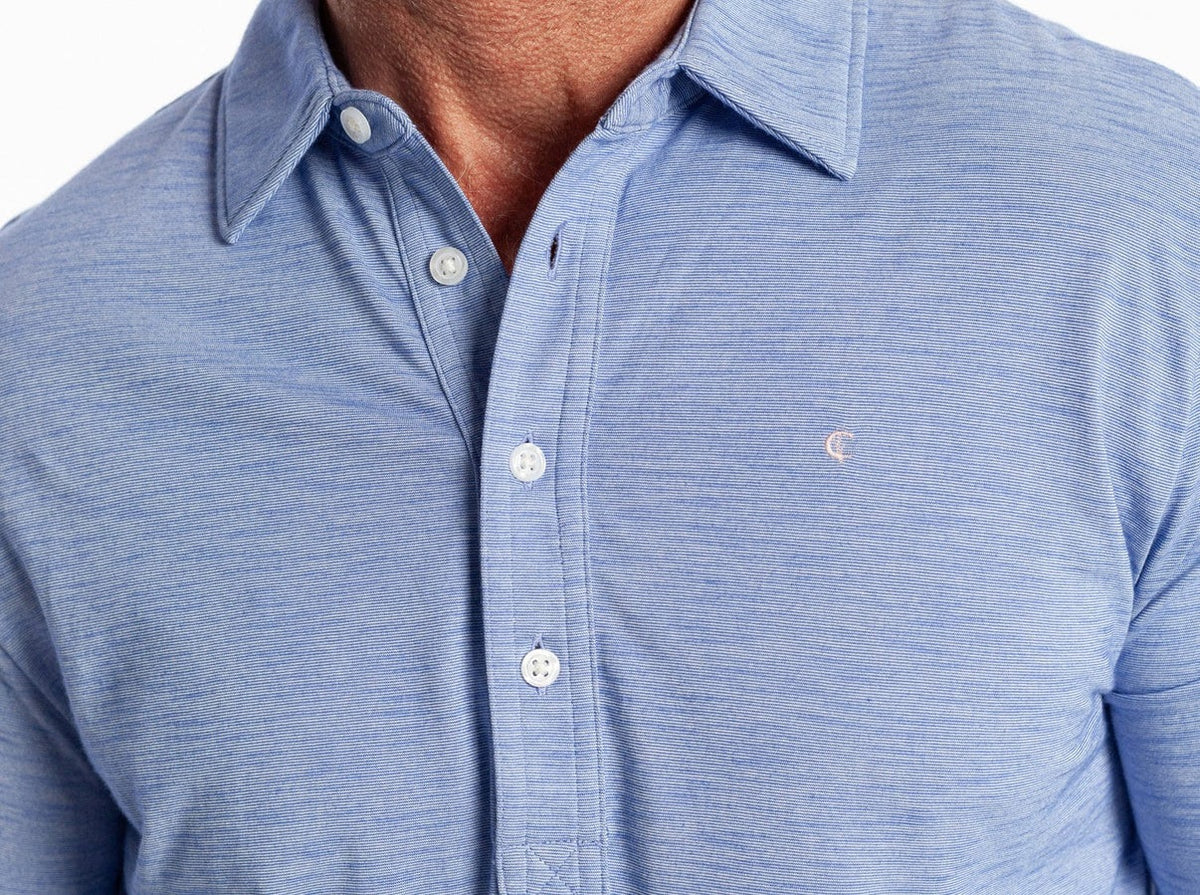 A smiling man with short gray hair and a beard is wearing the CRIQUET - BRRR° Long Sleeve Range Polo in Lapis Blue, standing against a plain white background.